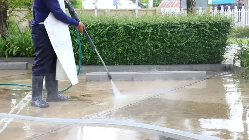 Person cleaning a cement patio