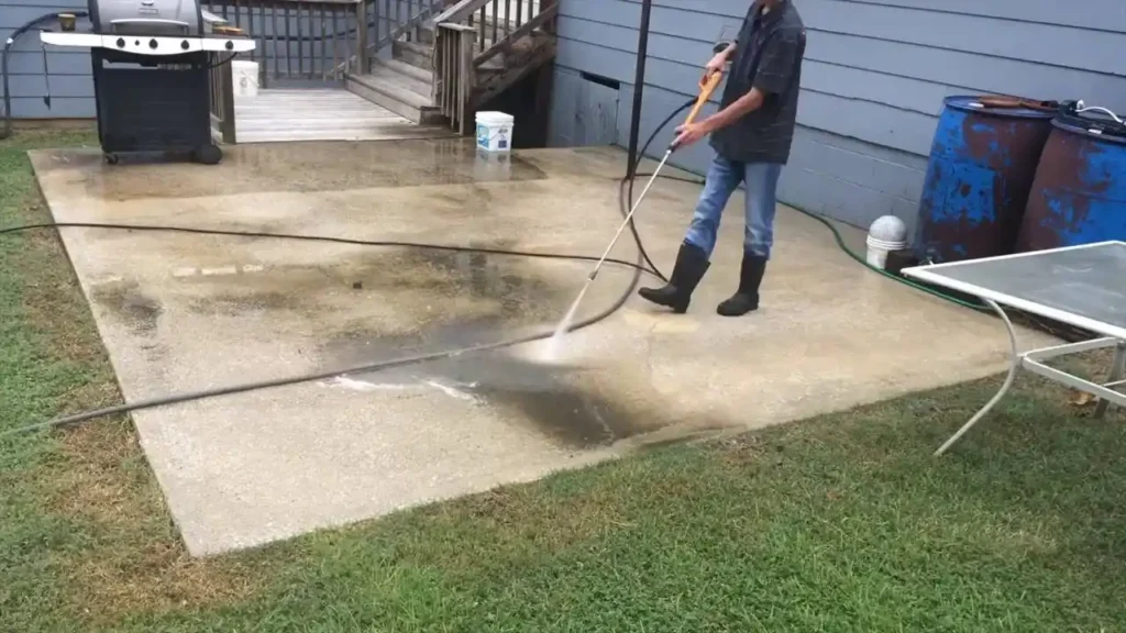 Person using a power washer to clean an outdoor concrete patio